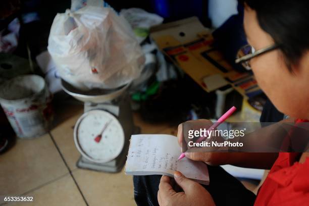 Woman records on Bank Sampah saving book. Bank Sampah is a small business unit in neighborhood community operated by volunteer housewives. They...