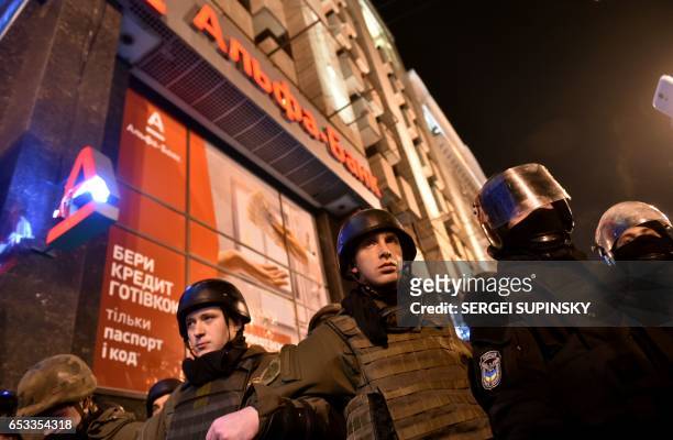 Ukrainian policemen guard as Ukrainian nationalists try to loot the Russian owned Alfa bank in Kiev on March 14 during a protest. The activists...