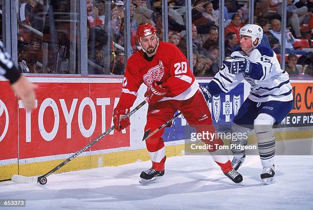 Martin Lapointe of the Detroit Red Wings gets ready to pass the puck as Tomas Kaberle of the Toronto Maple Leafs is behind him during the game at the...