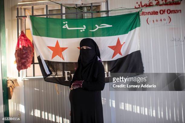 Malak Rifai a Syrian refugee from Daraa, poses for a portrait at nine months pregnant in front of a Syrian flag in her family's trailer in the...