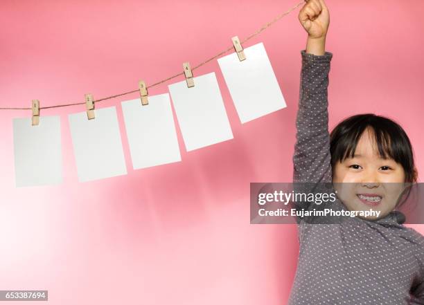 cute girl holding a clothesline with five sheets of white paper - new testament stockfoto's en -beelden