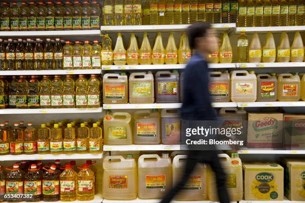 Customer walks past cooking oil displayed on shelves inside an Ocean Supercenter store, operated by City Mart Holdings Co., in Yangon, Myanmar, on...