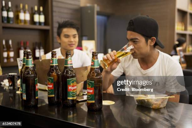 Customers drink Myanmar Beer, manufactured by Myanmar Brewery Ltd., at a bar inside a Marketplace by City Mart store, operated by City Mart Holdings...