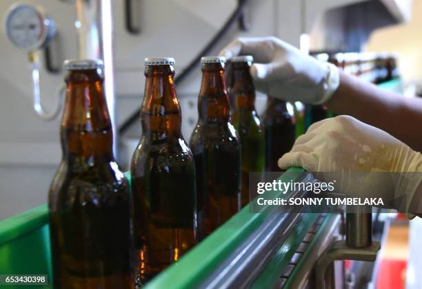 This picture taken on February 24, 2017 shows a worker checking bottles of beer at the Stark Beer factory in Singaraja, a regency on Indonesia's Bali...