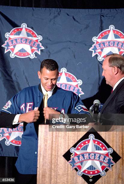 Alex Rodriguez tries on his new jersey during a press conference after being signed to the Texas Rangers at The Ball Park in Arlington,...