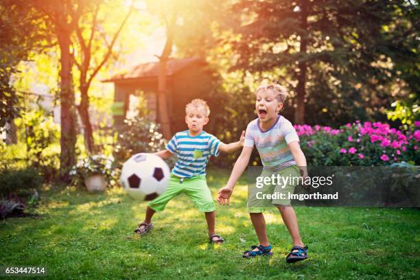 little boys playing football in the garden - ballkid stock pictures, royalty-free photos & images