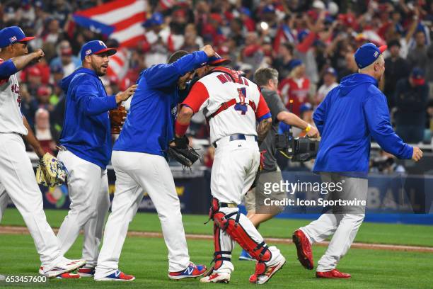 Puerto Rico players mob Puerto Rico Catcher Yadier Molina after they won 3-1 in a World Baseball Classic second round Pool F game against Dominican...