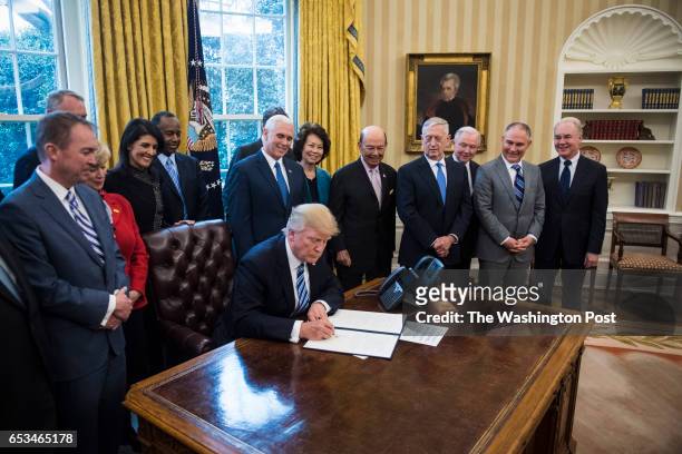 President Donald Trump signs an Executive Order entitled Comprehensive Plan for Reorganizing the Executive Branch in the Oval Office of the White...