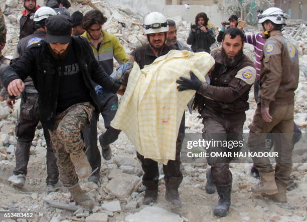 Members of the Syrian civil defence, known as the White Helmets, remove a victim from the rubble of a destroyed building following a reported air...