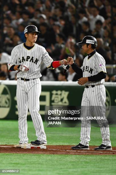 Infielder Hayato Sakamoto of Japan celebrates with coach Coach Nishi after hitting a single in the bottom of the second inning during the World...