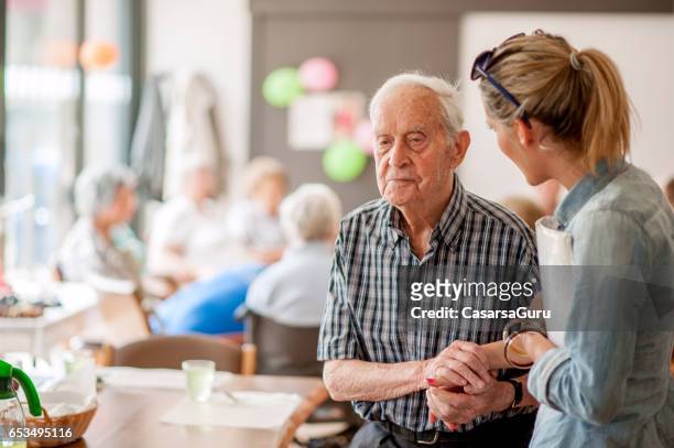 assistant in the community center giving advice to a senior man - dependency stock pictures, royalty-free photos & images