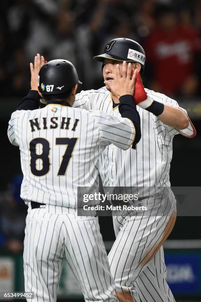 Outfielder Yoshitomo Tsutsugoh of Japan celebrates hitting a solo homerun with coach Toshihisa Nishi to make it 0-1 in the bottom of the sixth inning...