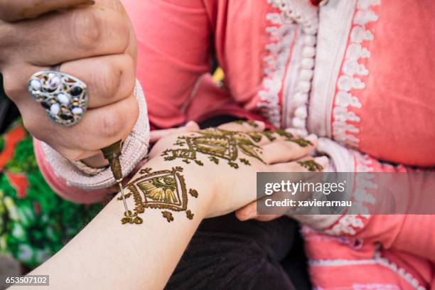 frau malerei henna auf die hand - hennatätowierung stock-fotos und bilder