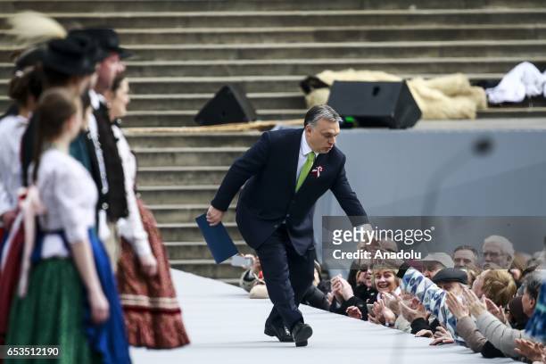 Hungarian Prime Minister Viktor Orban greets the crowd during Hungary's National Day celebrations, which also commemorates the 1848 Hungarian...