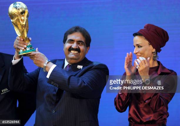 Emir of the State of Qatar Sheikh Hamad bin Khalifa Al-Thani poses by his wife Sheikha Moza bint Nasser Al-Missned with the World Cup trophy after...