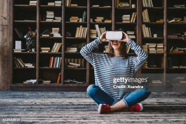 happy woman wearing vr glasses in front of bookshelves - ar glasses stock pictures, royalty-free photos & images