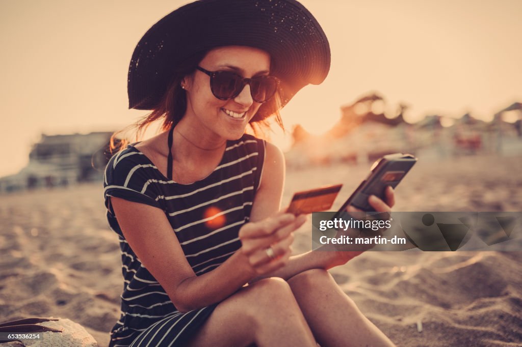 Woman at the beach shopping online with credit card