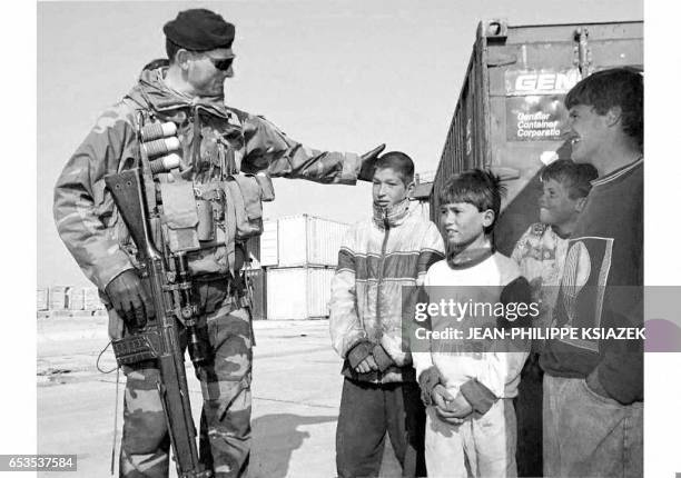 An Italian soldier speaks with Albanian children as the first of the Italian troops arrived in Durres 11 April as part of the Alba operation....