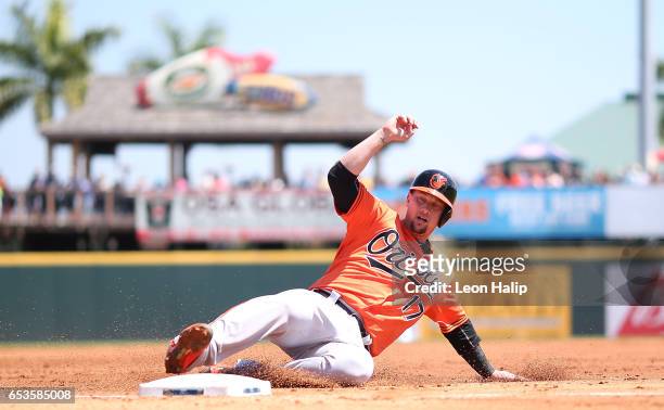Chris Johnson of the Baltimore Orioles slides into third base during the second inning of a spring training game against the Pittsburgh Pirates on...
