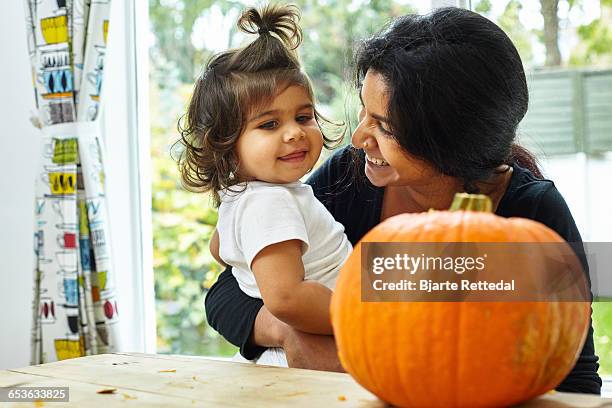 mother and baby daughter looking at carved pumpkin - bjarte rettedal stock pictures, royalty-free photos & images