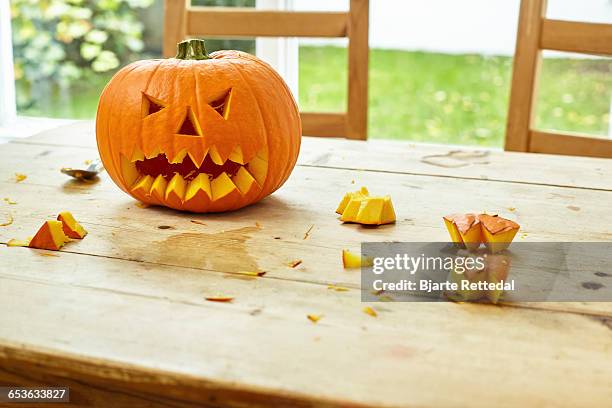 carved pumpkin on farmhouse table - scary pumpkin faces stock pictures, royalty-free photos & images