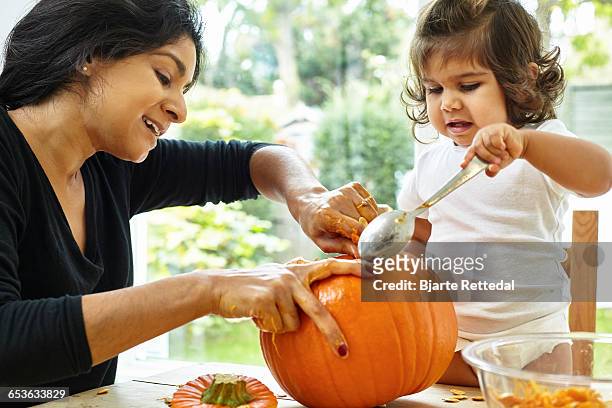 mother and baby daughter carving a pumpkin - asian mother and daughter pumpkin stockfoto's en -beelden