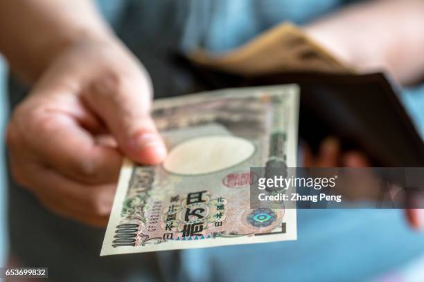 Girl take out a ten-thousand Yen banknote from her wallet. In the early march, Japan's core inflation has returned for the first time in more than...