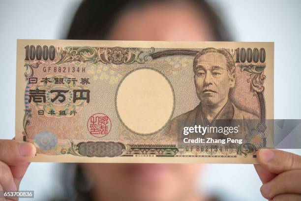 Girl holds a ten-thousand Yen bank note in hand. In the early march, Japan's core inflation has returned for the first time in more than one year and...