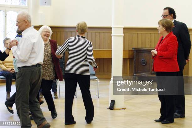 German Chancellor Angela Merkel and Father Martin von Essen look on as senior citizens dance at the Paul-Gerhadt-Stift center on March 16, 2017 in...