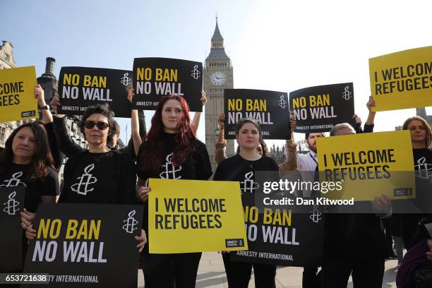 Amnesty International activists hold placards as they protest against US President Donald Trump's Travel ban, in Parliament Square on March 16, 2017...