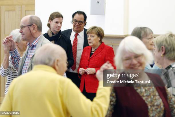 German Chancellor Angela Merkel and Father Martin von Essen look on as senior citizens dance at the Paul-Gerhadt-Stift center on March 16, 2017 in...