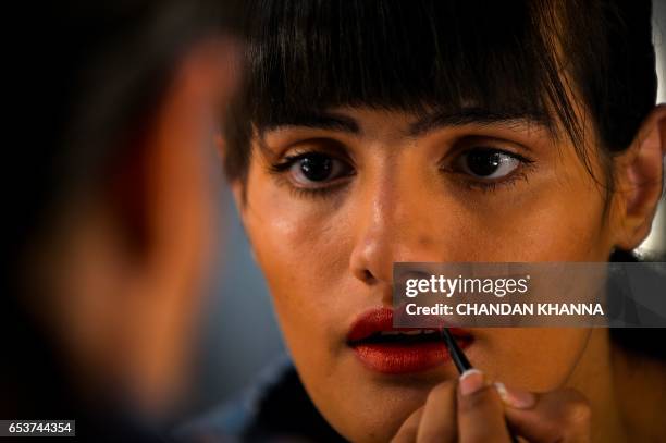 Model is reflected in a mirror as she applies lipstick ahead of the show by Indian designers Hemant and Nandita Lalwani during the Amazon India...