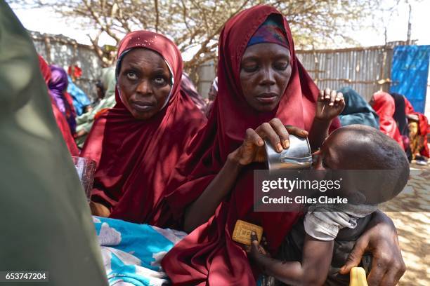 Somali mother gives water to her child at a World Food Program humanitarian aid registration center in Mogadishu. According to an United Nations...