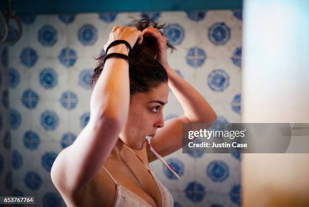 woman fixing her hair and brushing teeth at the same time - habit clothing stock pictures, royalty-free photos & images