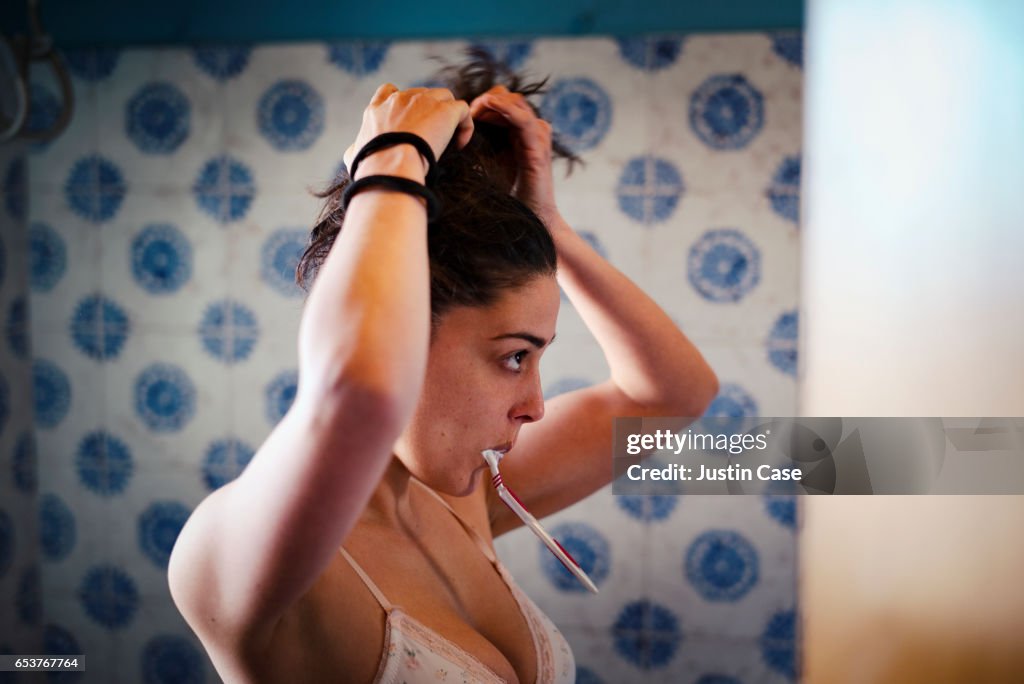 Woman fixing her hair and brushing teeth at the same time