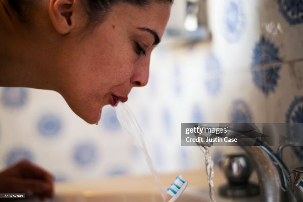 Woman spitting out water after brushing her teeth