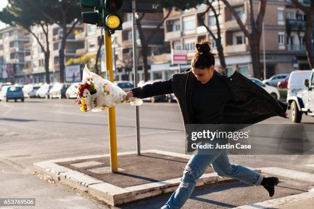 woman jumping happily with a bunch of flowers in her hand - torn gift stock pictures, royalty-free photos & images