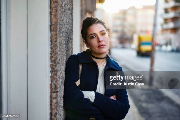 portrait of a woman leaning against a wall looking into camera - mezzo busto foto e immagini stock