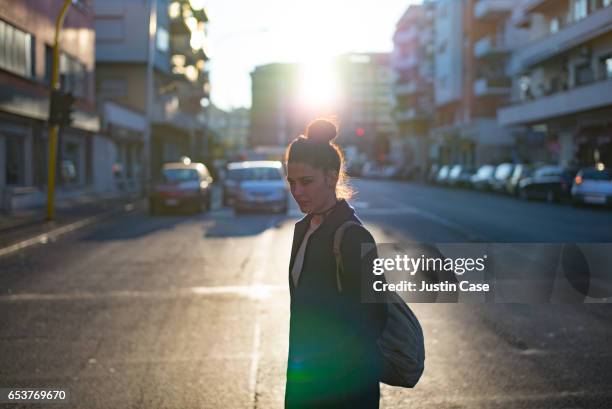 woman crossing a city street in the evening - topknot stock pictures, royalty-free photos & images