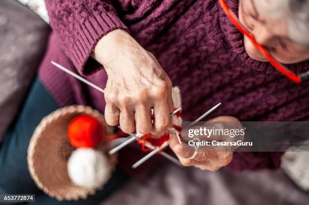 donna anziana con le mani artritiche che fanno uncinetto - mani fili foto e immagini stock