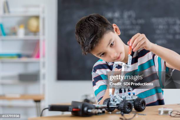 hübscher junge baut roboter in der schule - kids modern school life stock-fotos und bilder