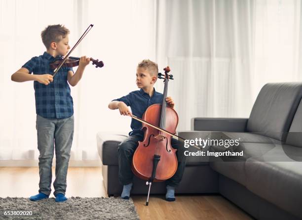 zwei kleine jungs üben cello und violine zusammen - violine stock-fotos und bilder