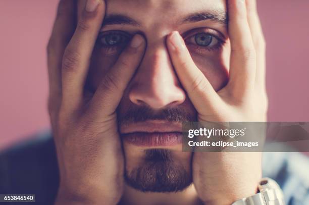 serious young man holding head - mens hair model stock pictures, royalty-free photos & images