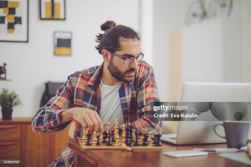 Young man playing chess at home