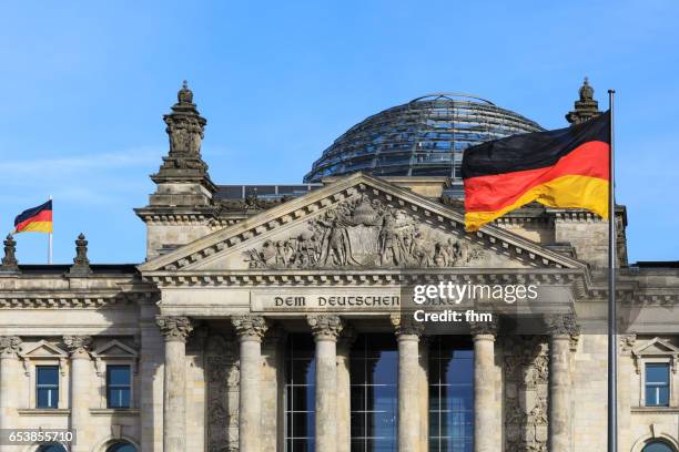 the famous inscription on the architrave on the west portal of the reichstag building in berlin: "dem deutschen volke" with german flag - reichstag photos et images de collection