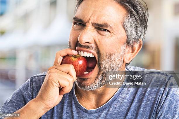 bearded man biting an apple - mordre photos et images de collection