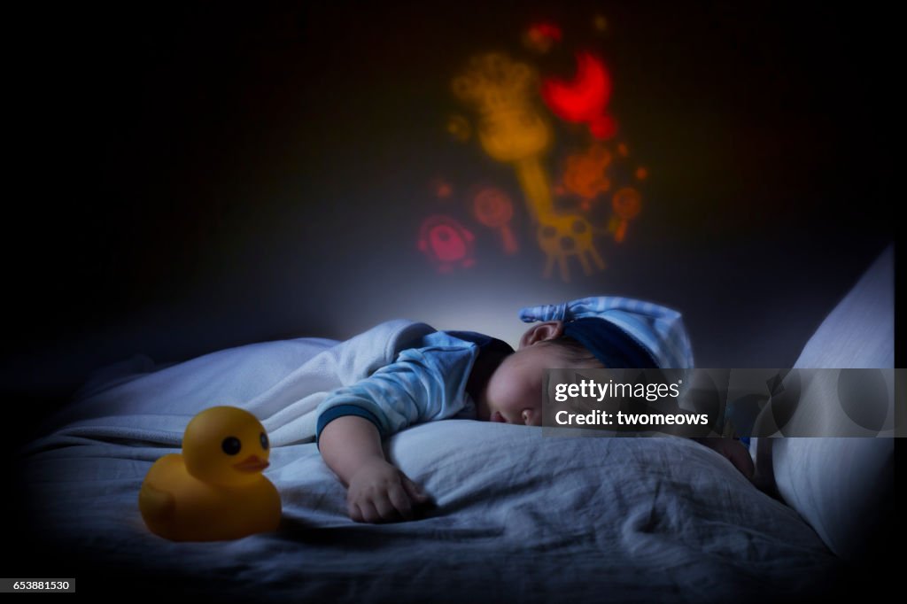 Asian toddler boy sleeping in the dark.
