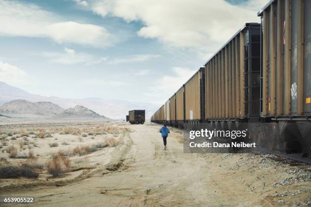 boy running alongside train cars - boy running track stock pictures, royalty-free photos & images