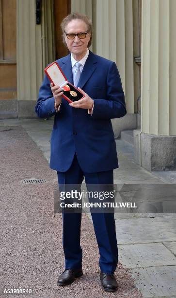 British musician Ray Davies of the sixties group The Kinks poses with his medal after he was knighted for services to music during an investiture...