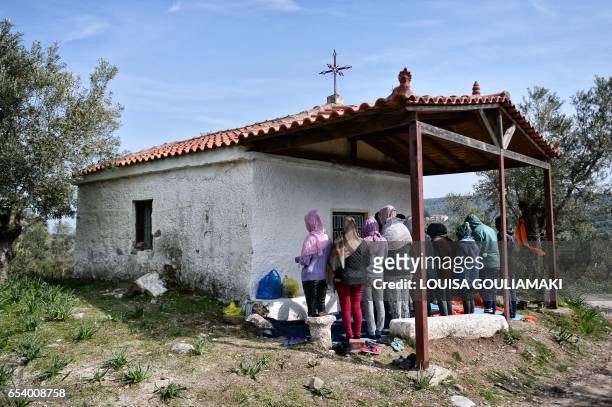 Picture taken on March 16, 2017 shows Christian African migrants praying at a hill church near the Moria migrant camp on the island of Lesbos, almost...
